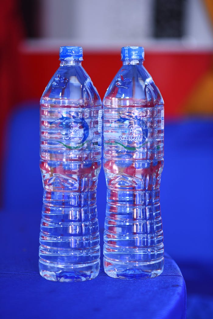 Two plastic water bottles on a blue table with colorful backdrop.