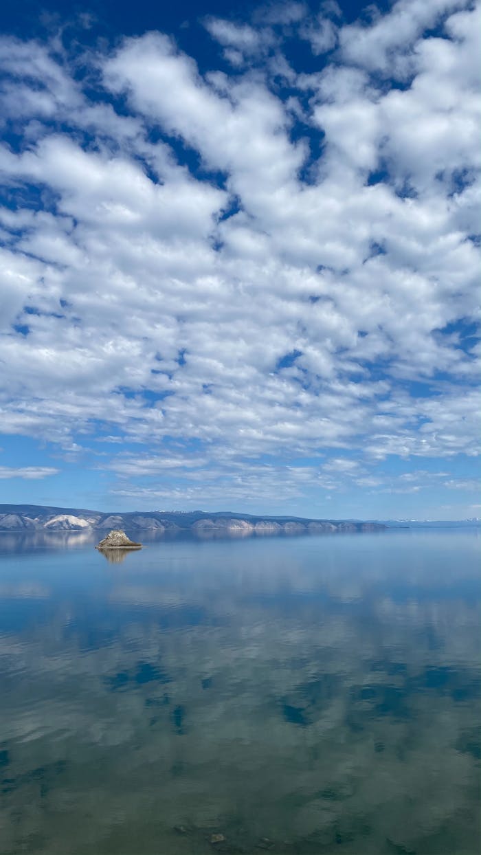 Tranquil view of Lake Baikal with clouds reflecting on calm waters in Russia.
